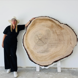Artist Tiffany Shlain stands next to large tree ring art, "Dendrofemonology."