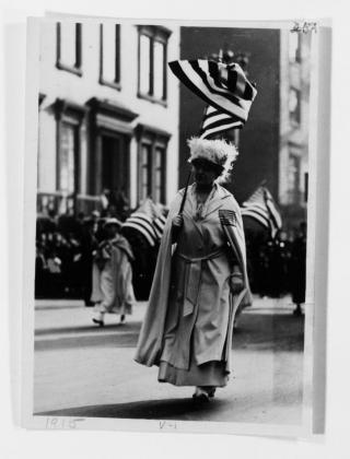 Carrie Chapman Catt carries a US flag while walking in the New York Suffrage Parade.