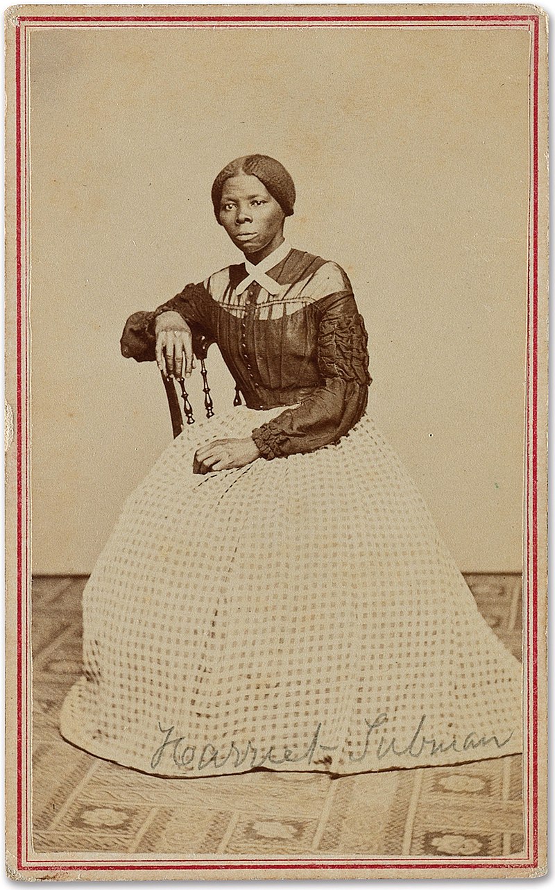 Harriet Tubman, sitting in chair, wearing a long-sleeved top and long skirt.