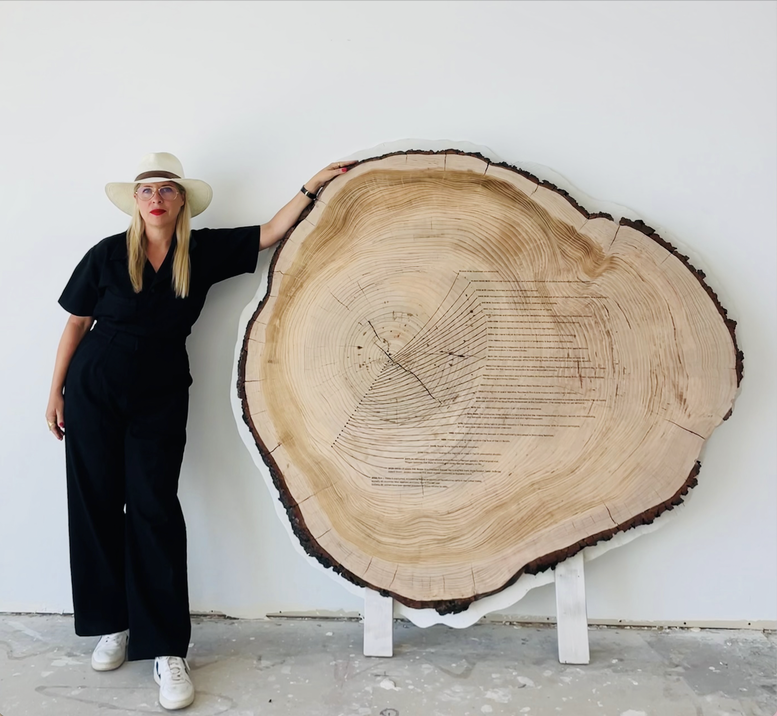 Artist Tiffany Shlain stands next to large tree ring art, "Dendrofemonology."