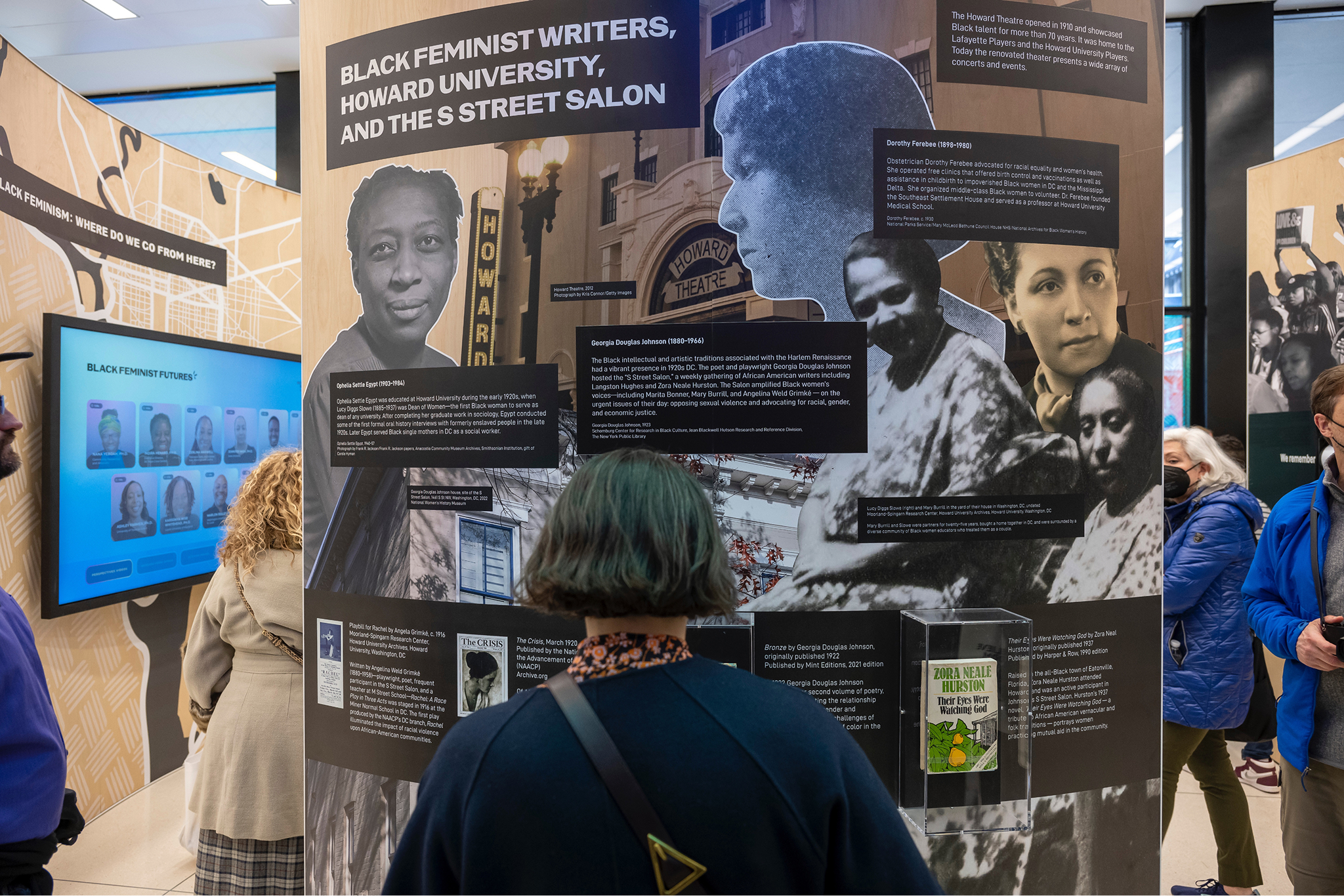 Young woman standing in front of exhibition wall.
