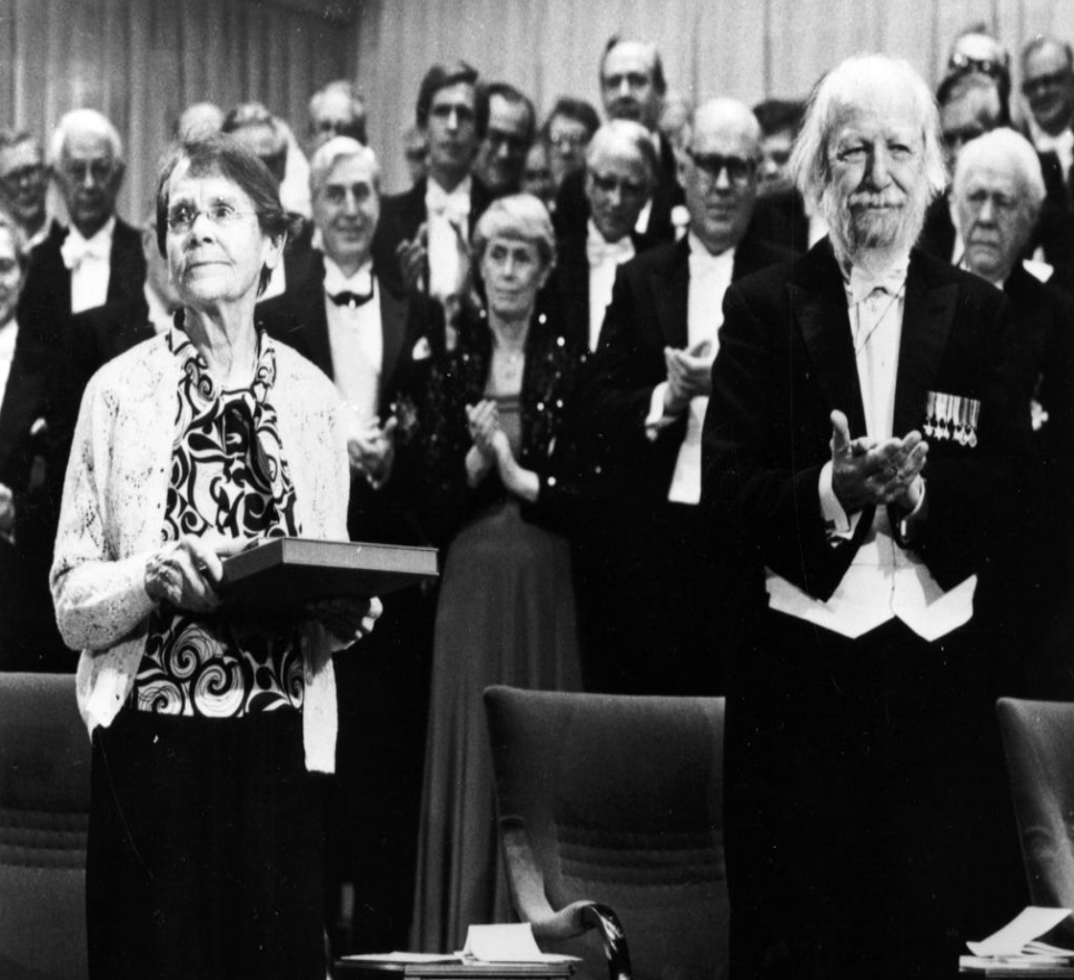 A crowd stands applauding McClintock as she receives the Nobel Prize