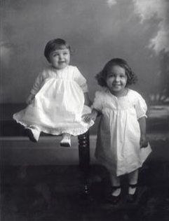 Black and white photo of two young girls dressed in white.