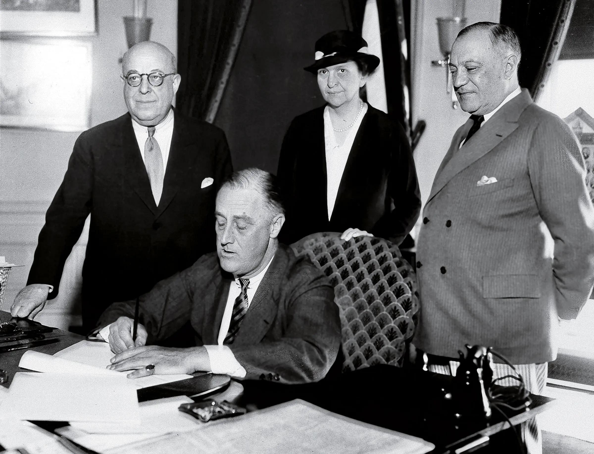 Perkins stands behind President Franklin D. Roosevelt as he signs a bill