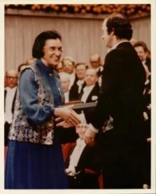 Photo of Rosalyn Yalow receiving the Nobel Prize. She is smiling and shaking the hand of the presenter.