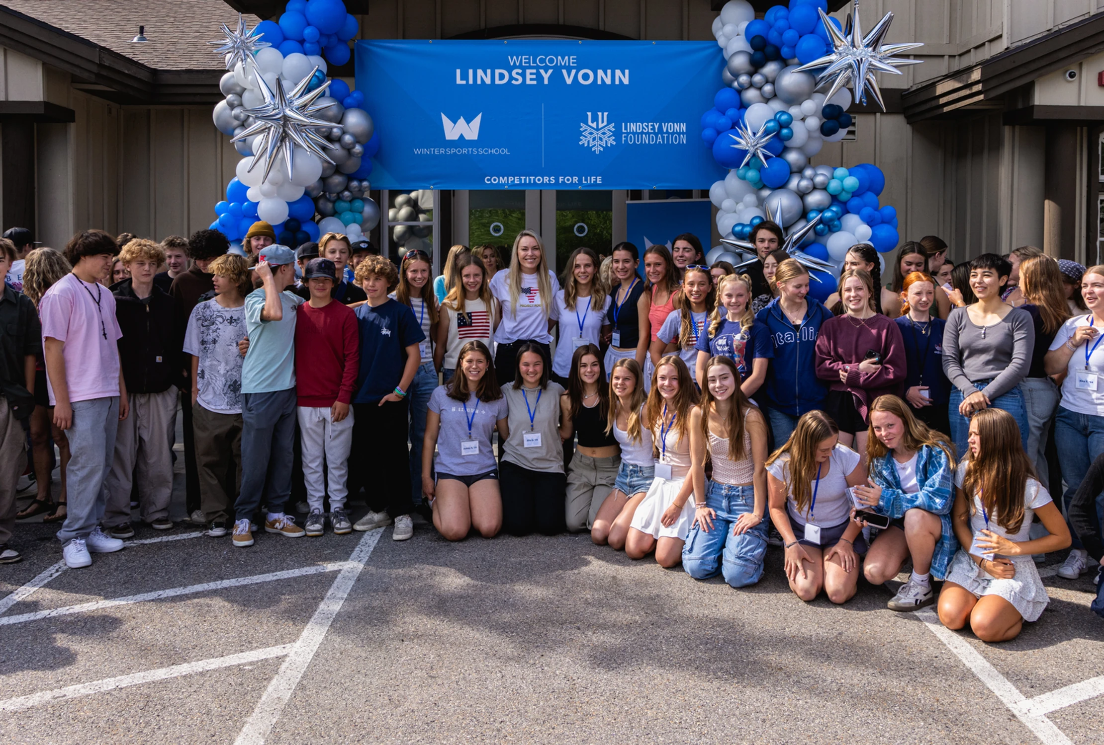Photo of Lindsey Vonn (center) posing with youth at the Winter Sports School.