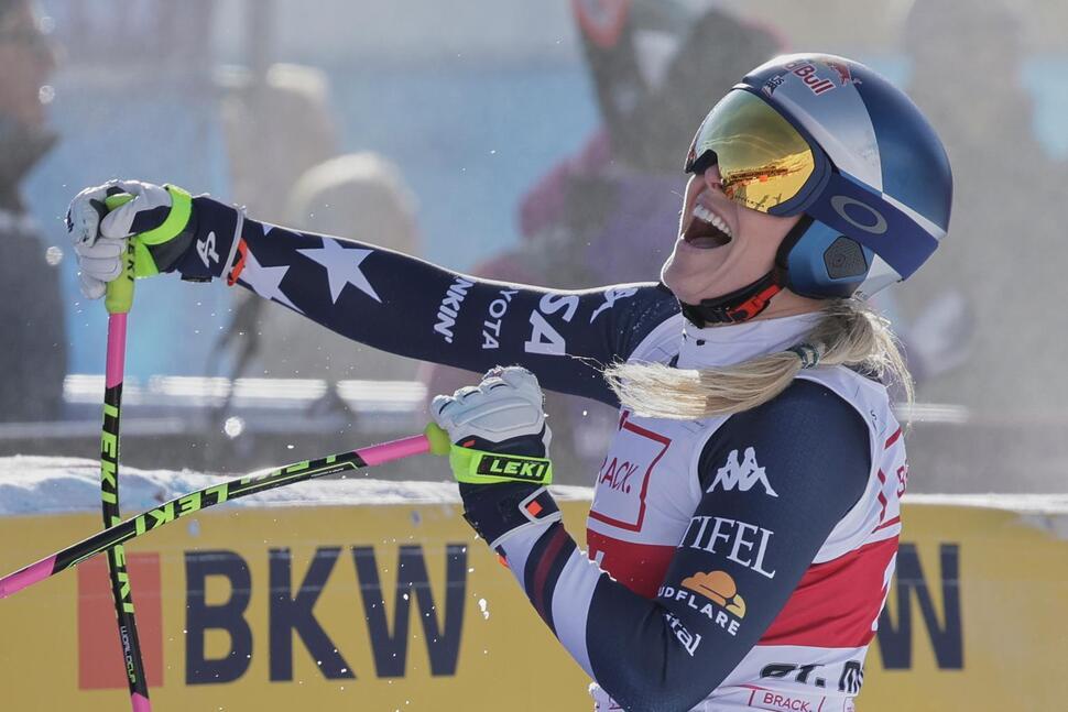 Photo of Lindsey Vonn celebrating after crossing the finish line. She is in her ski gear, and she is smiling wide with her head lifted up.